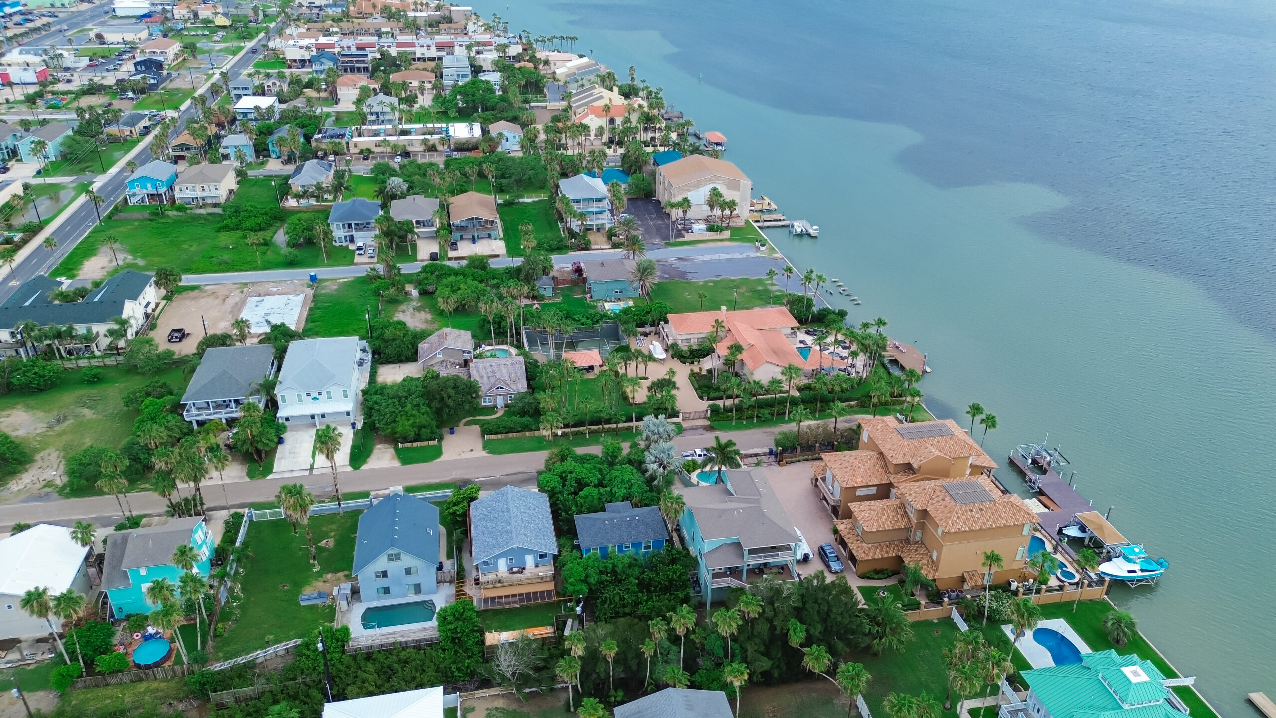 Private jetty yacht beach access from luxury mansion houses, villas with swimming pool, palm trees, upscale residential neighborhood in South Padre Island, Texas Gulf Coast vacation, aerial view. USA
